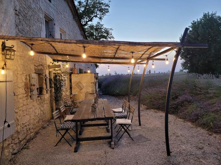 a wooden table and chairs under a pergola at Authentiek landhuis met zwembad in Dordogne. in Goûts-Rossignols