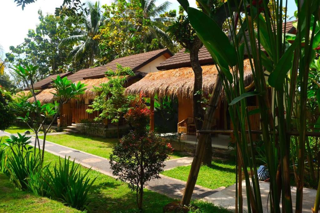 una casa con techo de paja en un jardín en Waroeng Senaru, en Senaru