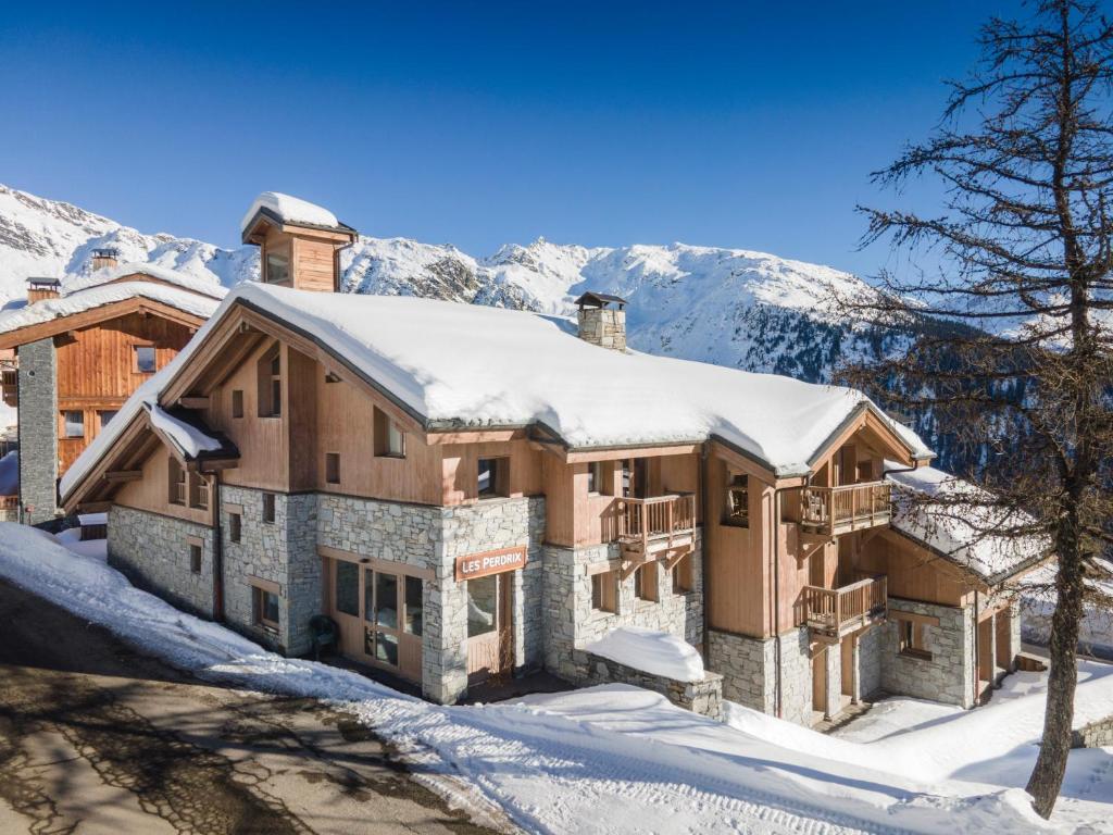 Chalets Les Perdrix - Mountain Collection في لا روزيير: منزل مغطى بالثلج مع جبال في الخلفية