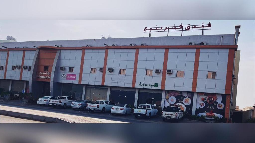 Un gran edificio con coches aparcados delante. en Fakher Yanbu Hotel, en Yanbu