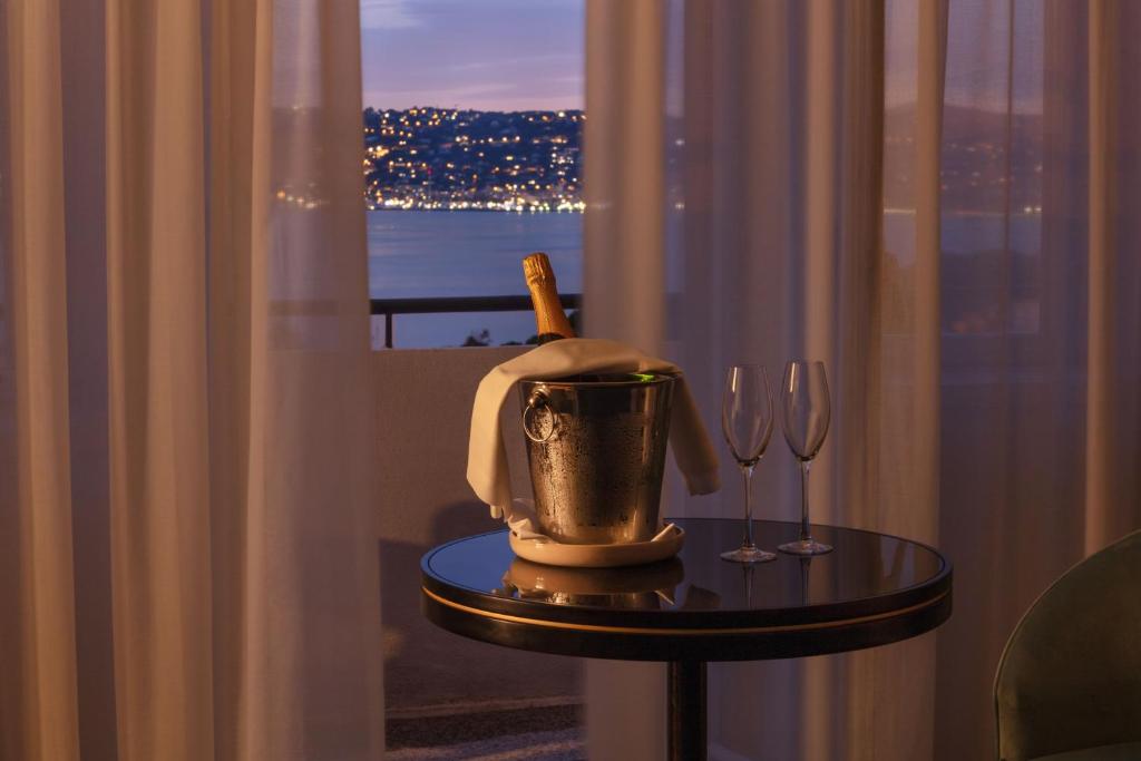 a table with a bottle of wine and wine glasses at The 1932 Hotel & Spa Cap d'Antibes - MGallery Collection in Juan-les-Pins