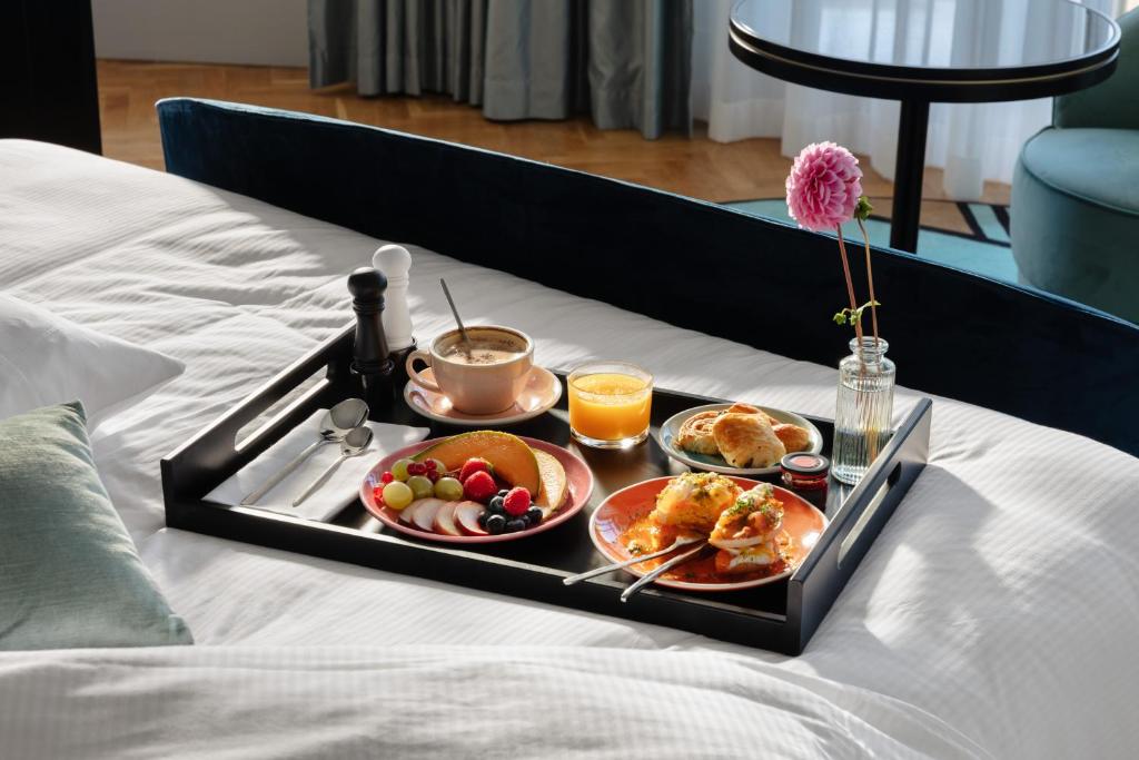 a tray of breakfast foods on a bed at The 1932 Hotel & Spa Cap d'Antibes - MGallery Collection in Juan-les-Pins