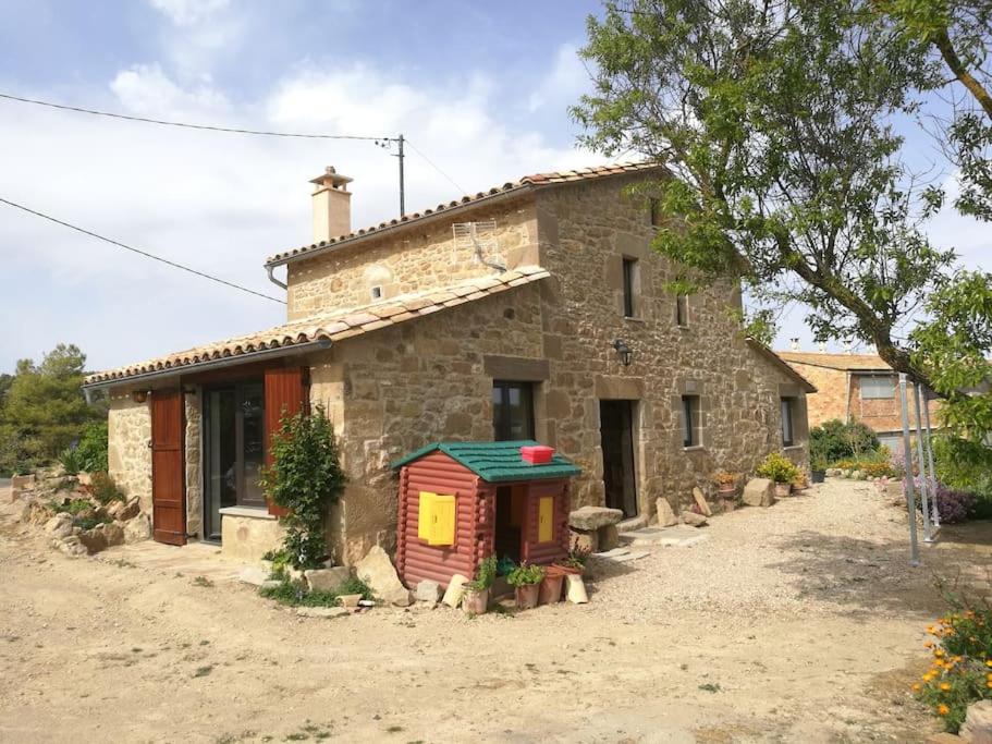 a stone house with a smallshed in front of it at Cal Sastre in Olíus