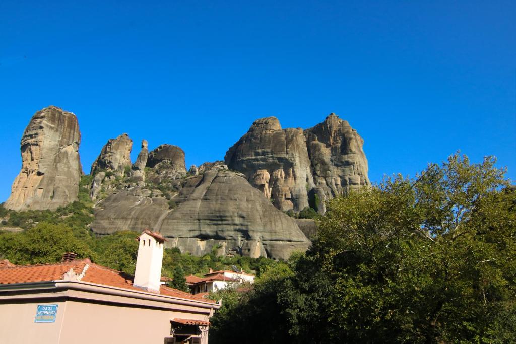 a building in front of a mountain with rocks at The house under the rocks of Meteora 2 in Kalabaka
