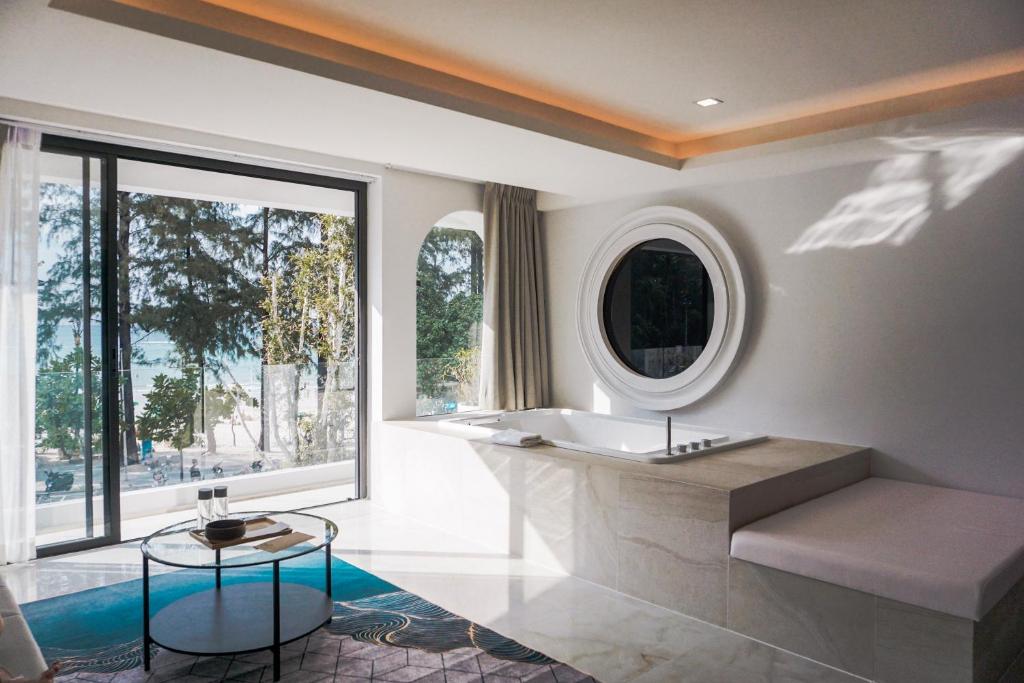a bathroom with a tub and a large window at Anona Beachfront Phuket Resort-SHA EXTRA PLUS in Patong Beach