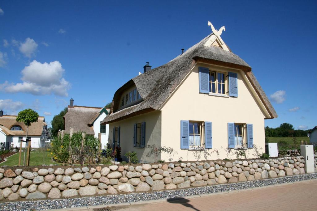 een wit huis met een rieten dak en een stenen muur bij Ankerplatz - a64767 in Kramerhof