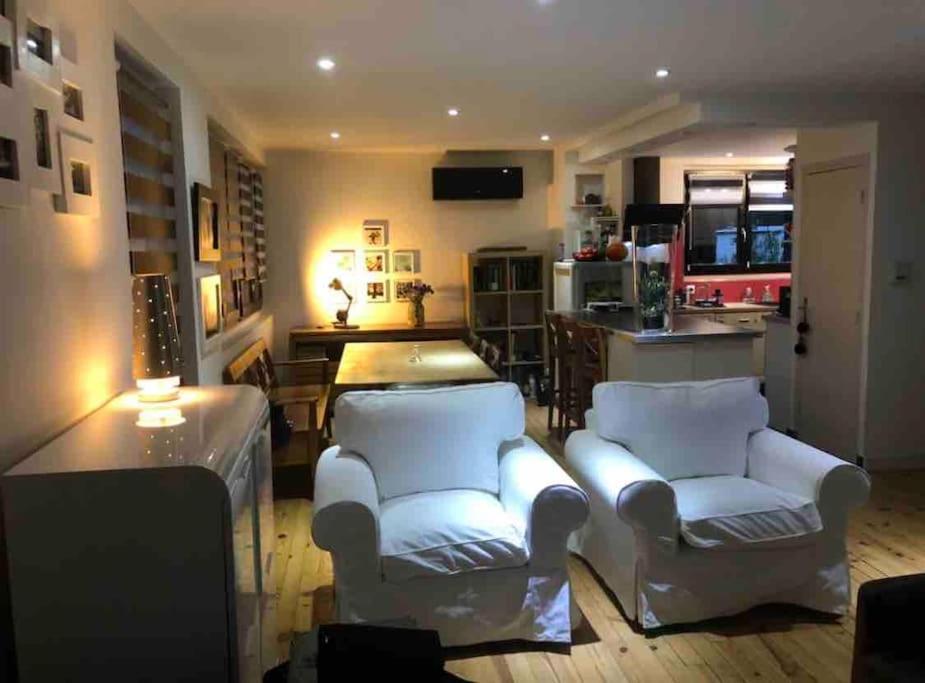sala de estar con 2 sillas blancas y cocina en Villa avec piscine, terrasse, jardin et vue…, en Bort-les-Orgues