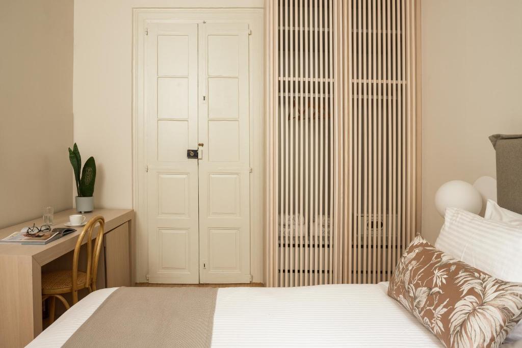 a bedroom with a bed and a desk and a door at SYROS SOUL LUXURY SUITES in Ermoupoli