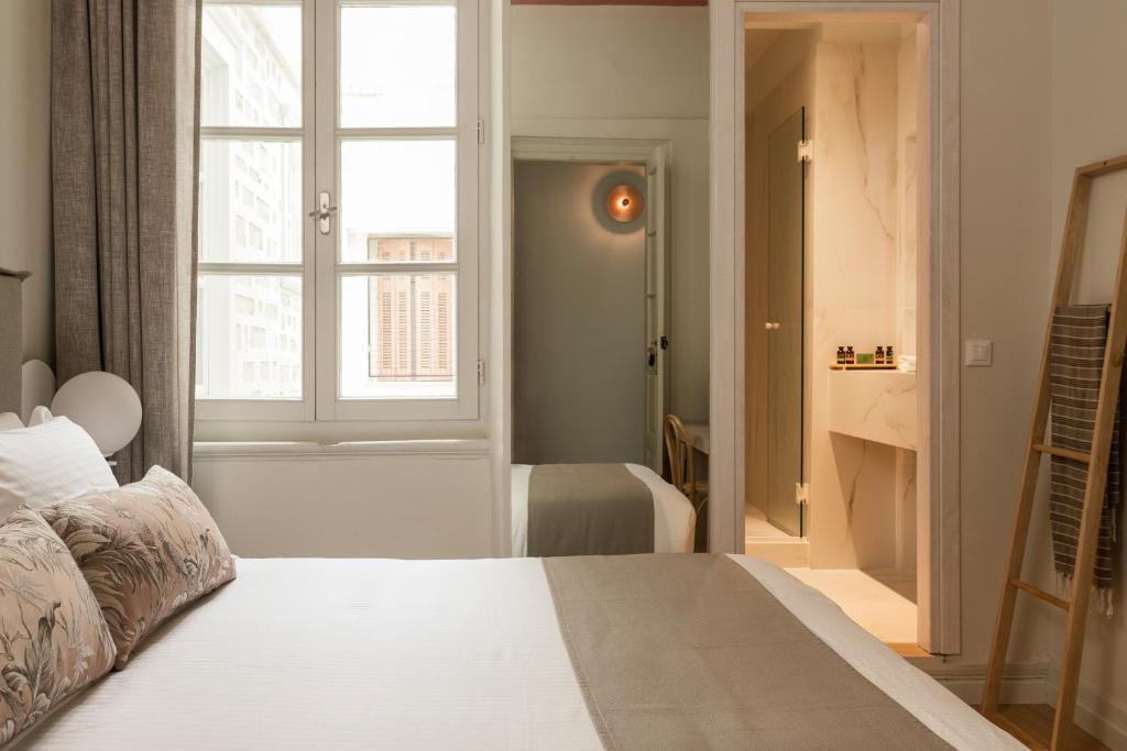 a bedroom with a white bed with a window at SYROS SOUL LUXURY SUITES in Ermoupoli