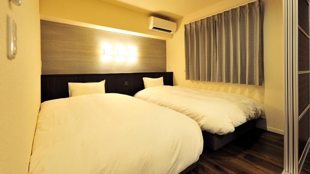 two beds in a room with white sheets at RakutenSTAY x Shamaison Osaka Dekijima - 106 in Osaka