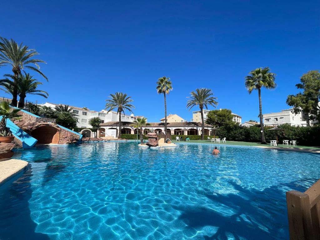 a pool at a resort with palm trees at Bungalow Laumar - Jávea in Jávea