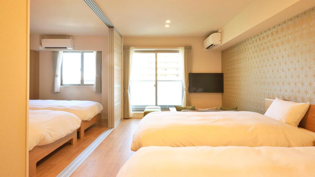 a hotel room with two beds and a tv at RakutenSTAY x Shamaison Osaka Dekijima - 103 in Osaka