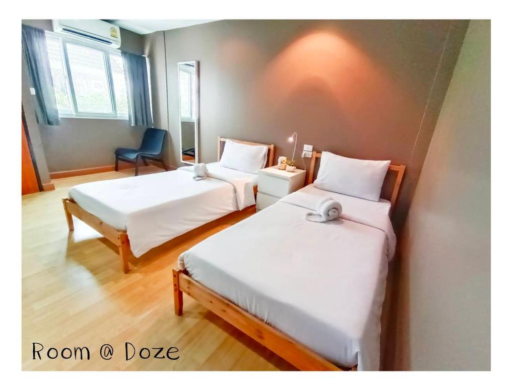 um quarto com duas camas e uma cadeira em Room@Doze em Nonthaburi