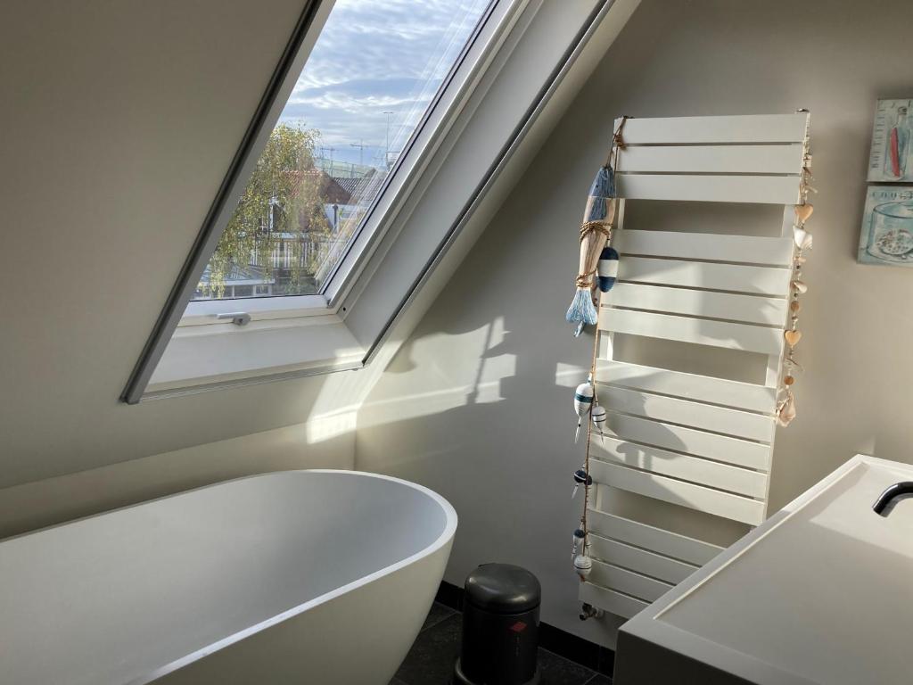 een badkamer met een wit bad en een raam bij Koetshuis aan het water 3 bedroom villa in Voorburg