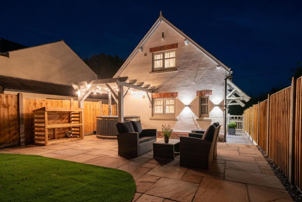 a patio with chairs and an umbrella in front of a house at Pilgrim Cottage in Tarvin