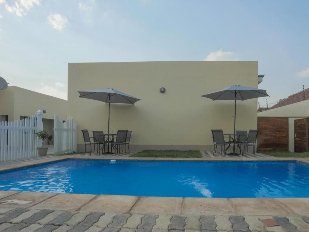 a pool with chairs and umbrellas next to a building at Pebble View Luxury Apartments in Lusaka