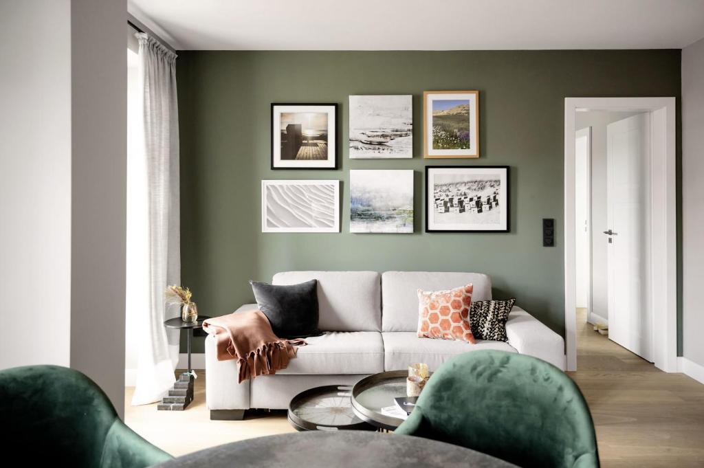 a living room with a white couch and a green wall at Living Lorens No 2 in Westerland (Sylt)