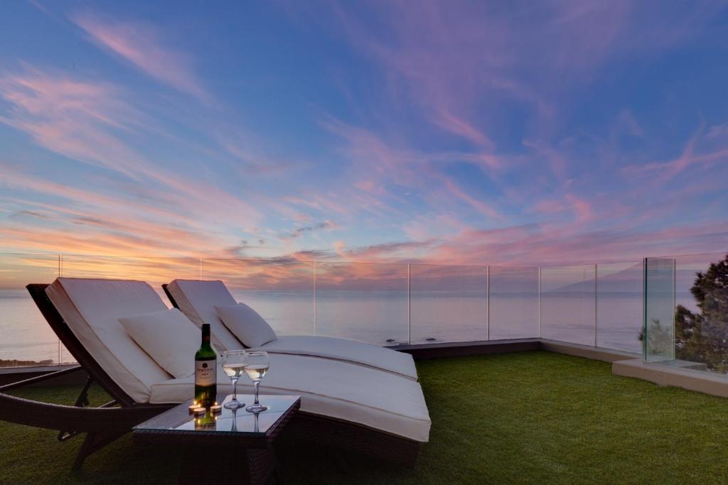 un patio con sillas blancas y una botella de vino en Atlantic Gold, en Ciudad del Cabo