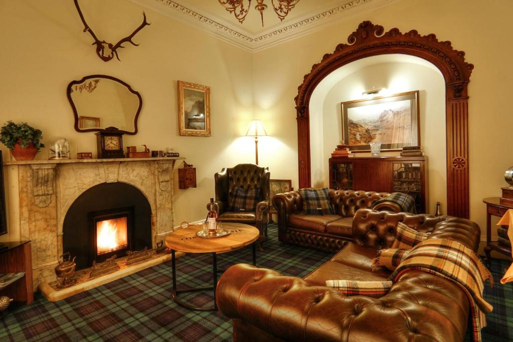 a living room with leather furniture and a fireplace at The Tannochbrae in Dufftown