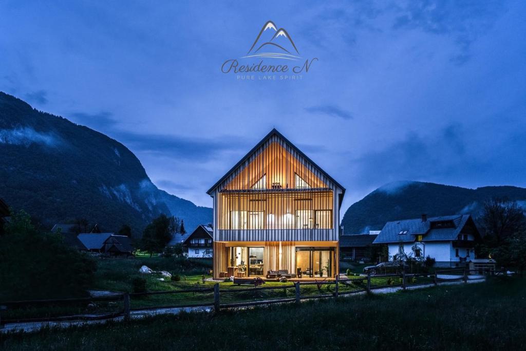 a house in a field with mountains in the background at Residence Novak Bohinj in Bohinj