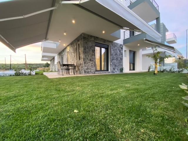 a house with a green lawn in front of it at Olea Suites 1 in Nea Moudania