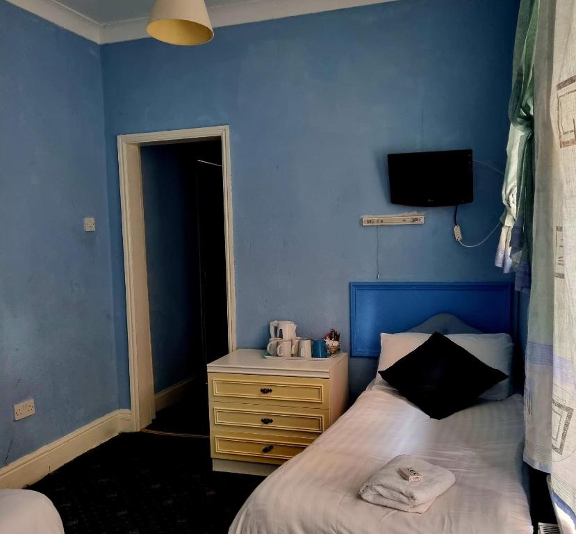 a blue bedroom with a bed and a night stand at The New Osterley Hotel in Blackpool