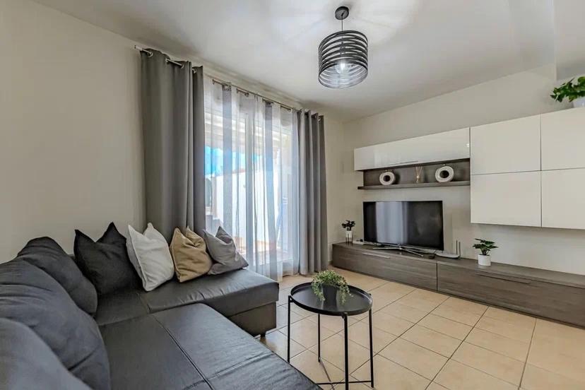 uma sala de estar com um sofá cinzento e uma televisão em Tenerifeopenhome Townhouse Oasis Fañabe 21 em Adeje