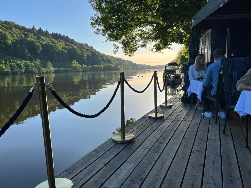 un gruppo di persone seduti su un molo vicino a un lago di Fischerstüberl a Gaishofen