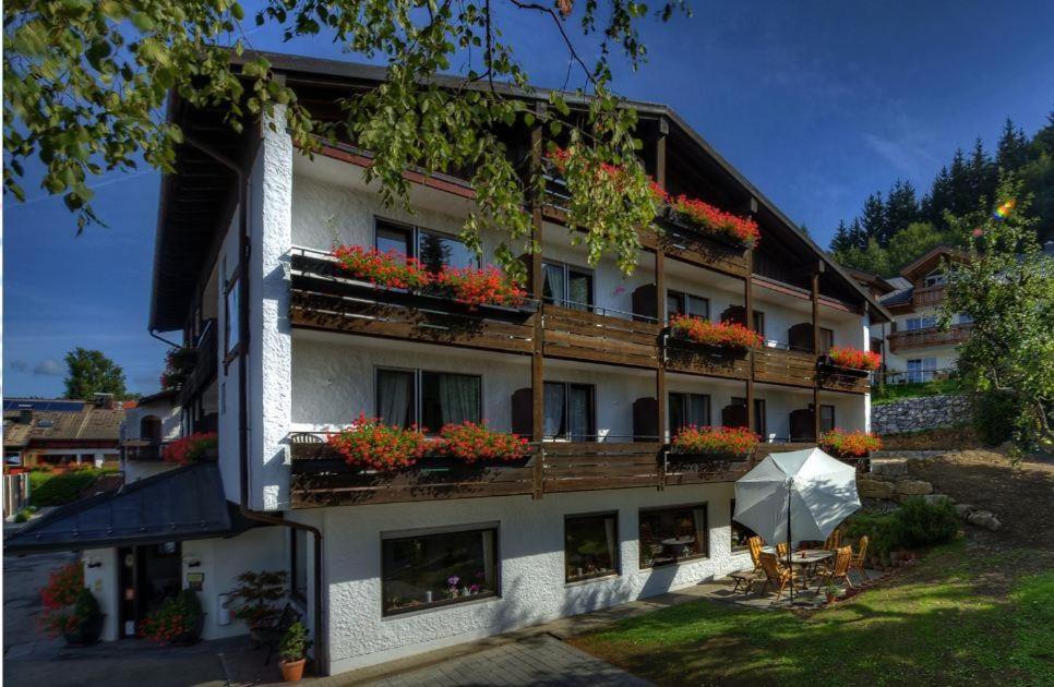 a building with flowers on the balconies and an umbrella at Alpenhof Ferienwohnungen in Oberstaufen