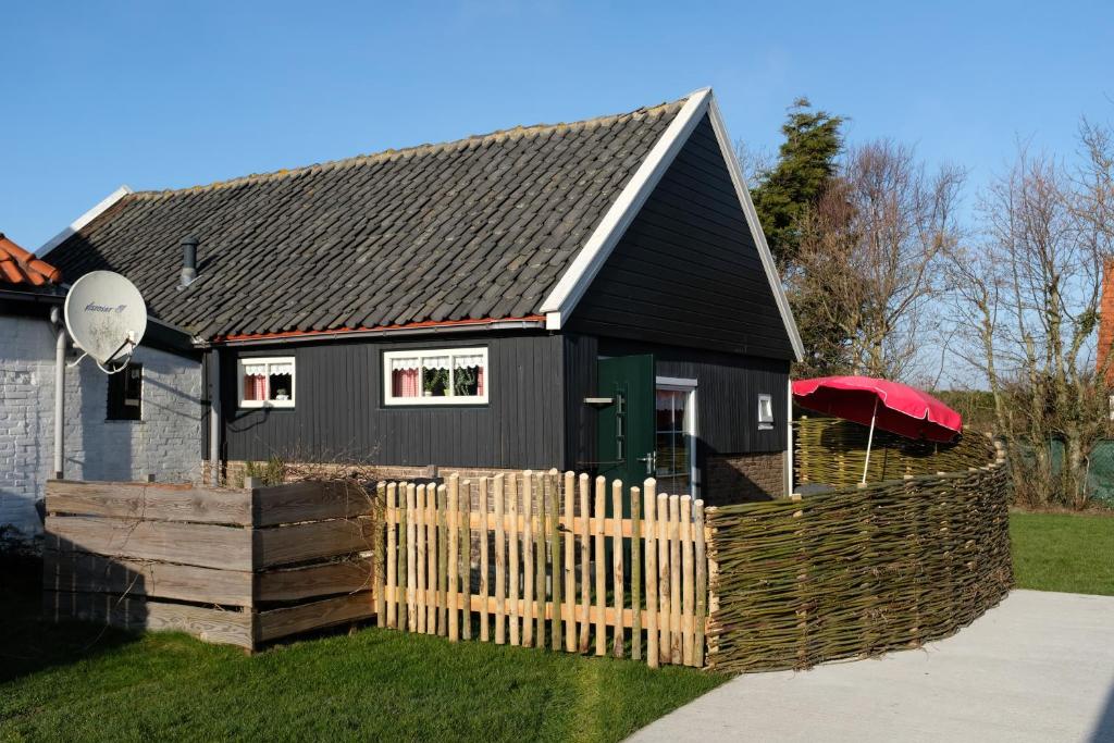 a black house with a wooden fence in front of it at de Koeboet in Callantsoog