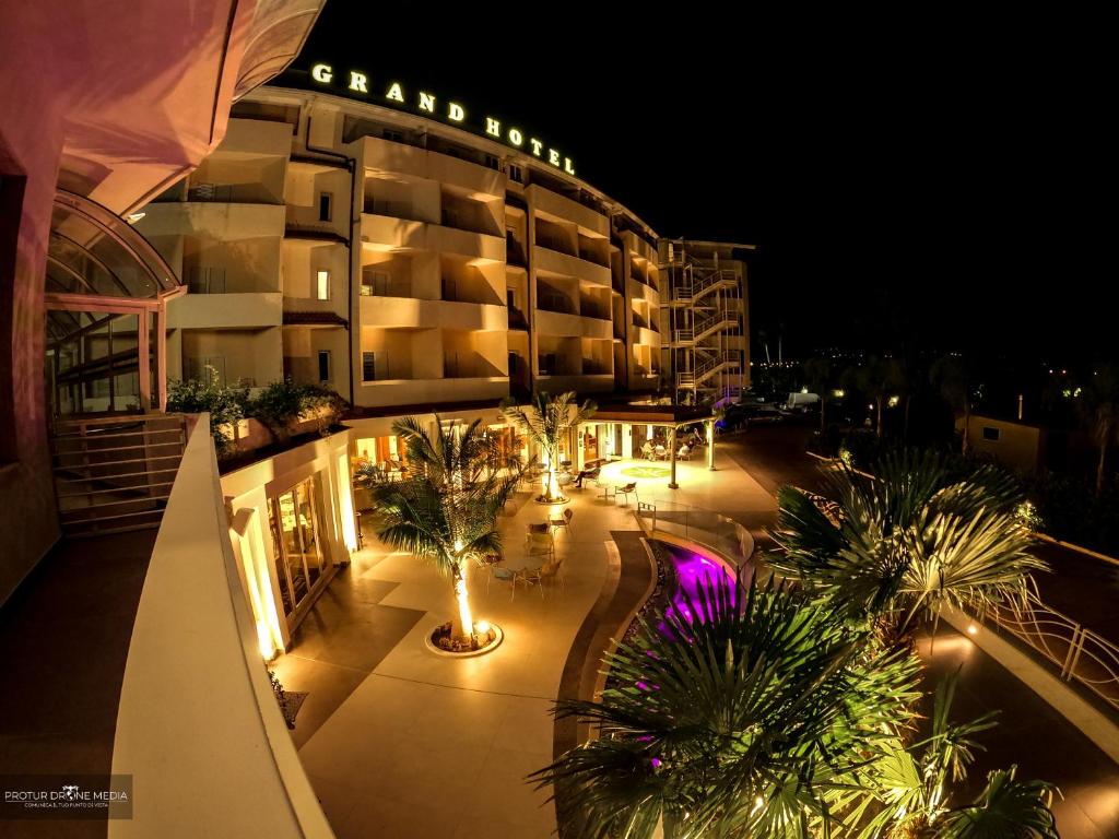 ein Hotel in der Nacht mit Palmen und Lichtern in der Unterkunft Grand Hotel President in Siderno Marina