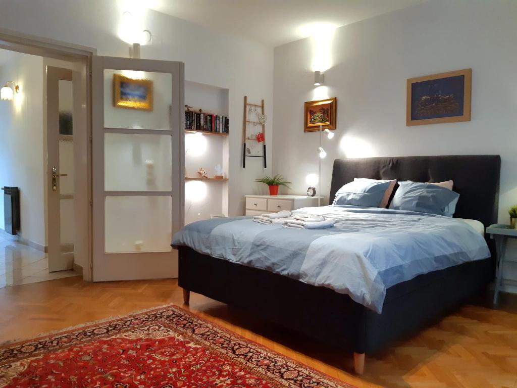 a bedroom with a bed with blue sheets and a rug at My Miracle Apartment in Zagreb
