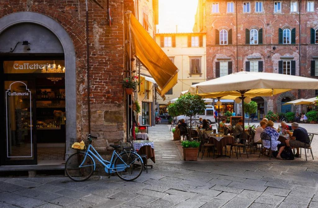 una strada con persone sedute ai tavoli con ombrelloni di Loft il Chiostro della Cattedrale a Lucca