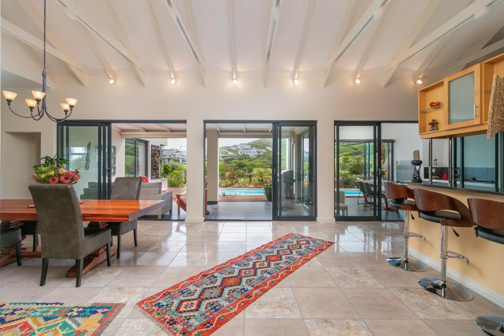 a dining room with a table and chairs and glass doors at Pezula Ocean Vista Luxury in Knysna