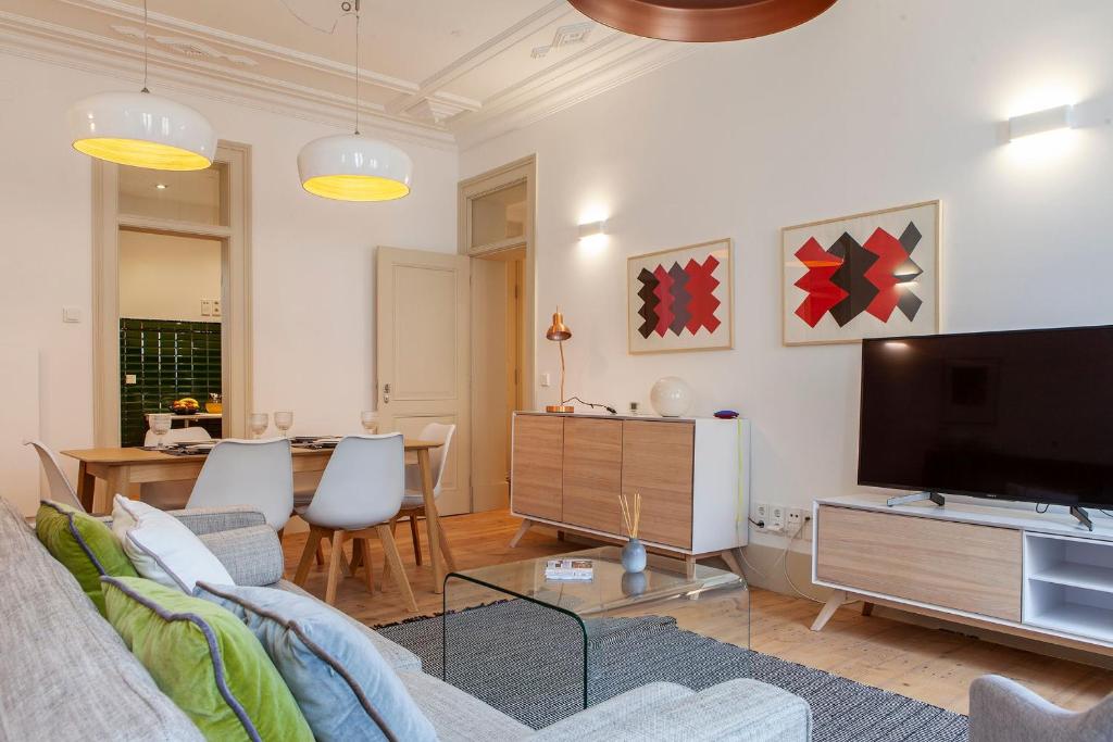 Charming 2BDR Apartment in Lapa by LovelyStay في لشبونة: غرفة معيشة مع أريكة وتلفزيون بشاشة مسطحة