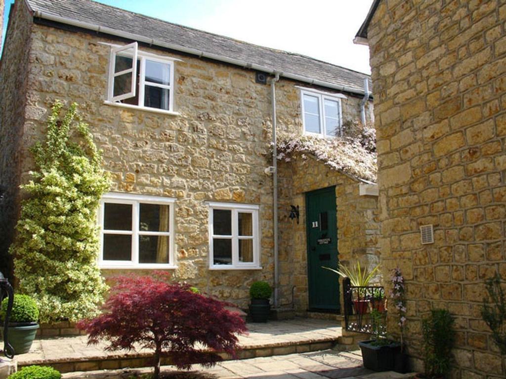 a brick house with a green door and a yard at Fiddlesticks Cottage in Beaminster