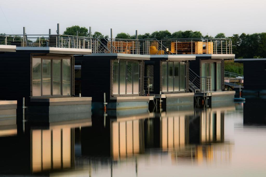 une maison assise au-dessus d'une masse d'eau dans l'établissement Hausboot Wangermeer Nordsonne12 mit Sauna, à Wangerland