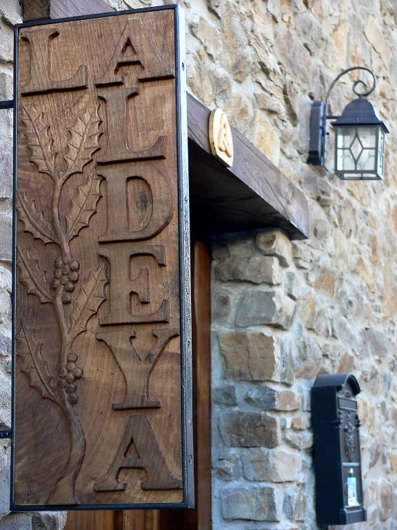 a wooden door with a tree sign on a stone wall at Hostal De Montaña La Aldeya in Villablino