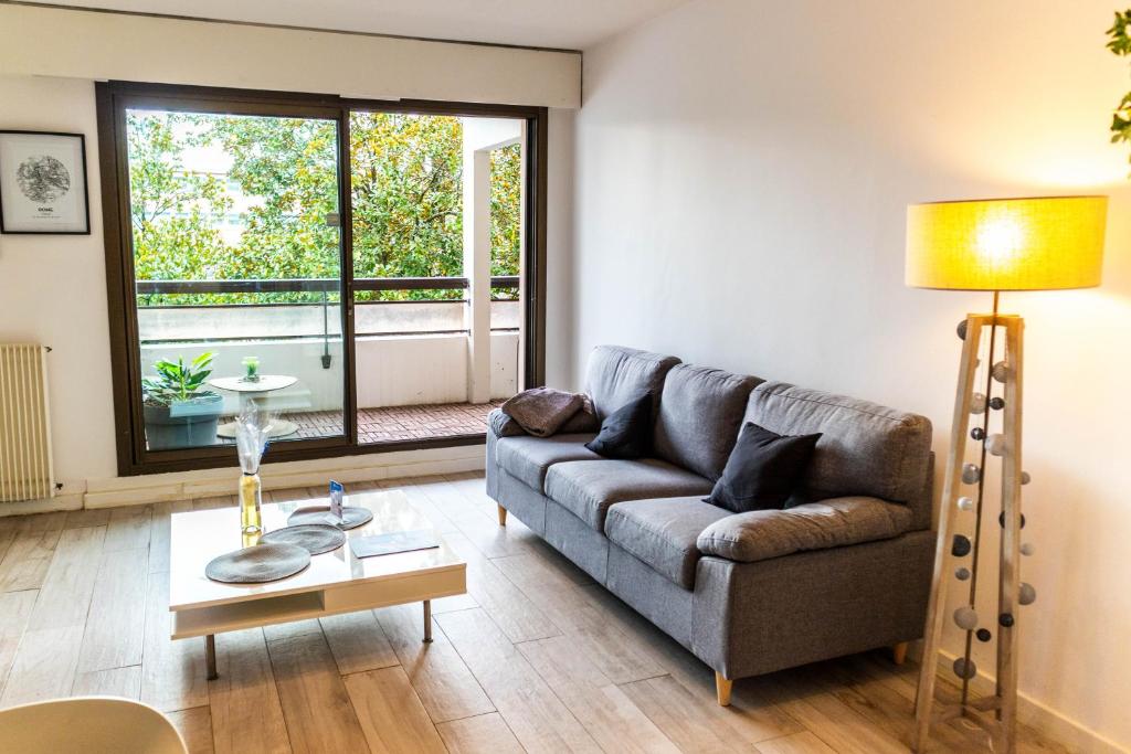 uma sala de estar com um sofá e uma mesa em Le Sperata - Bel appartement en centre ville avec 2 chambres, terrasse et parking em Pau