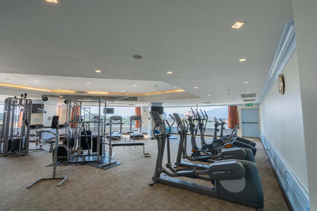 A bright hotel gym with cardio machines, strength equipment, and exterior-facing windows.