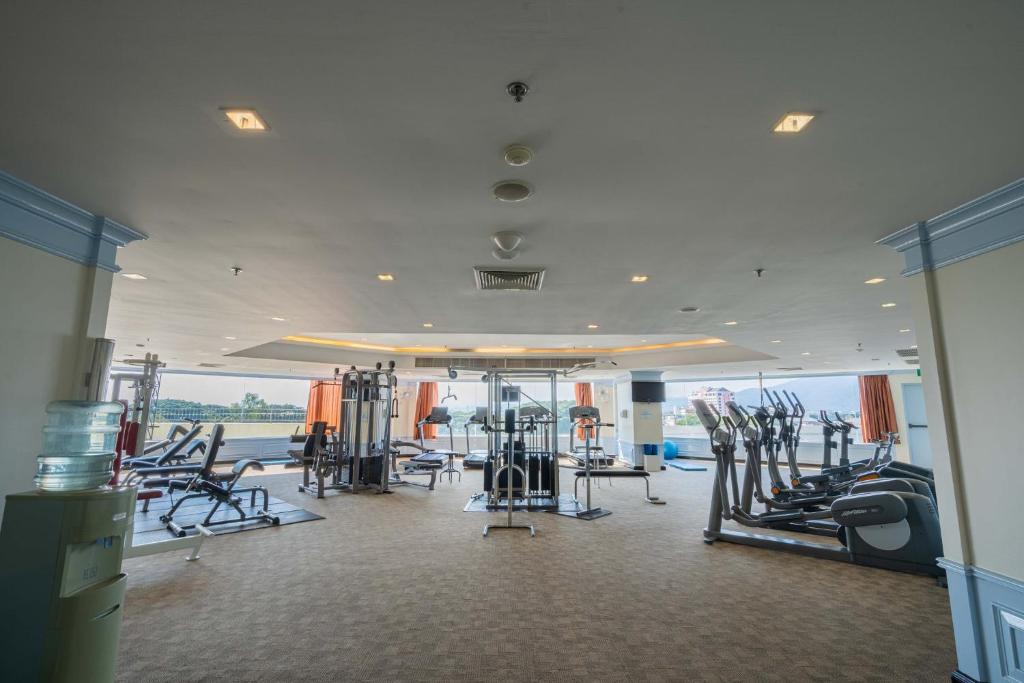 A large open fitness room with cardio and resistance equipment arranged around broad windows.