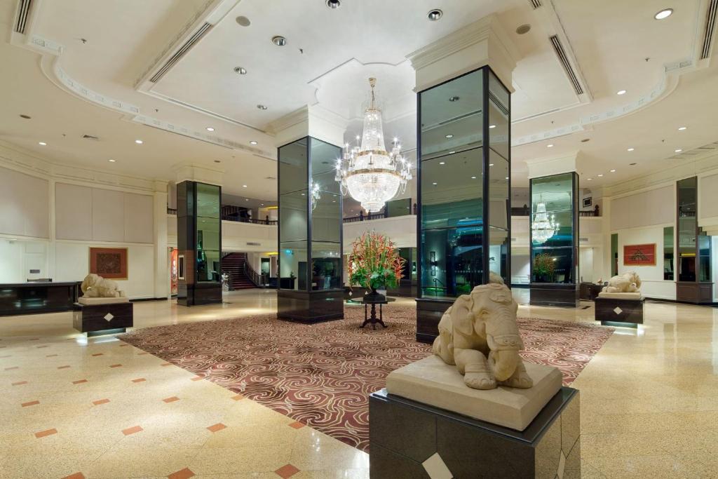 A grand marble-floored lobby centered on a chandelier, floral display, and elephant statues.