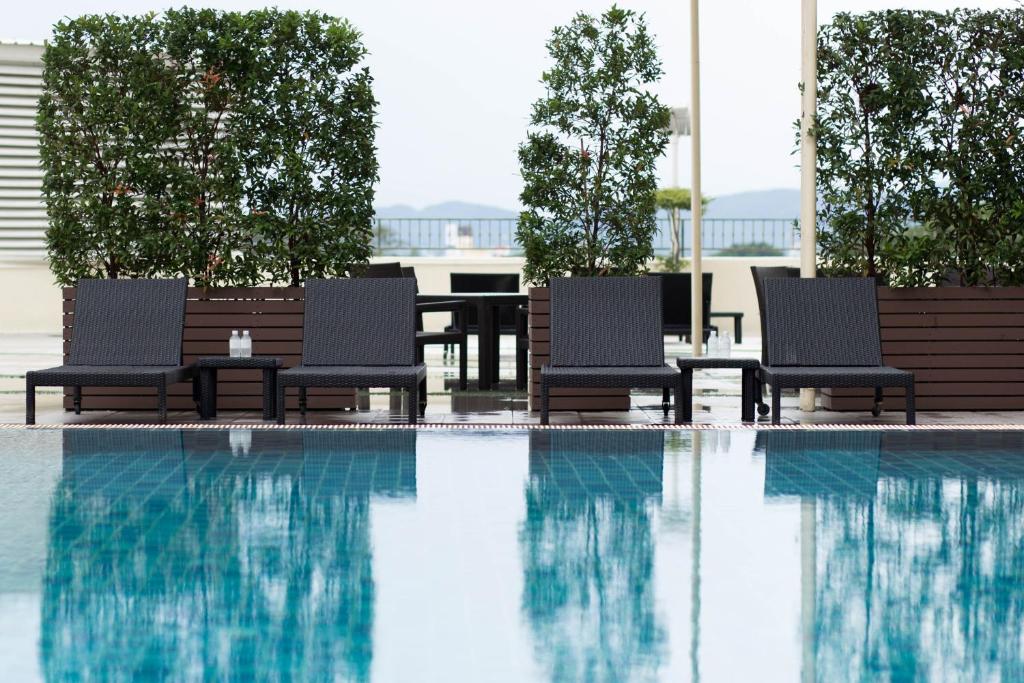 Poolside loungers arranged behind a reflective blue swimming pool.