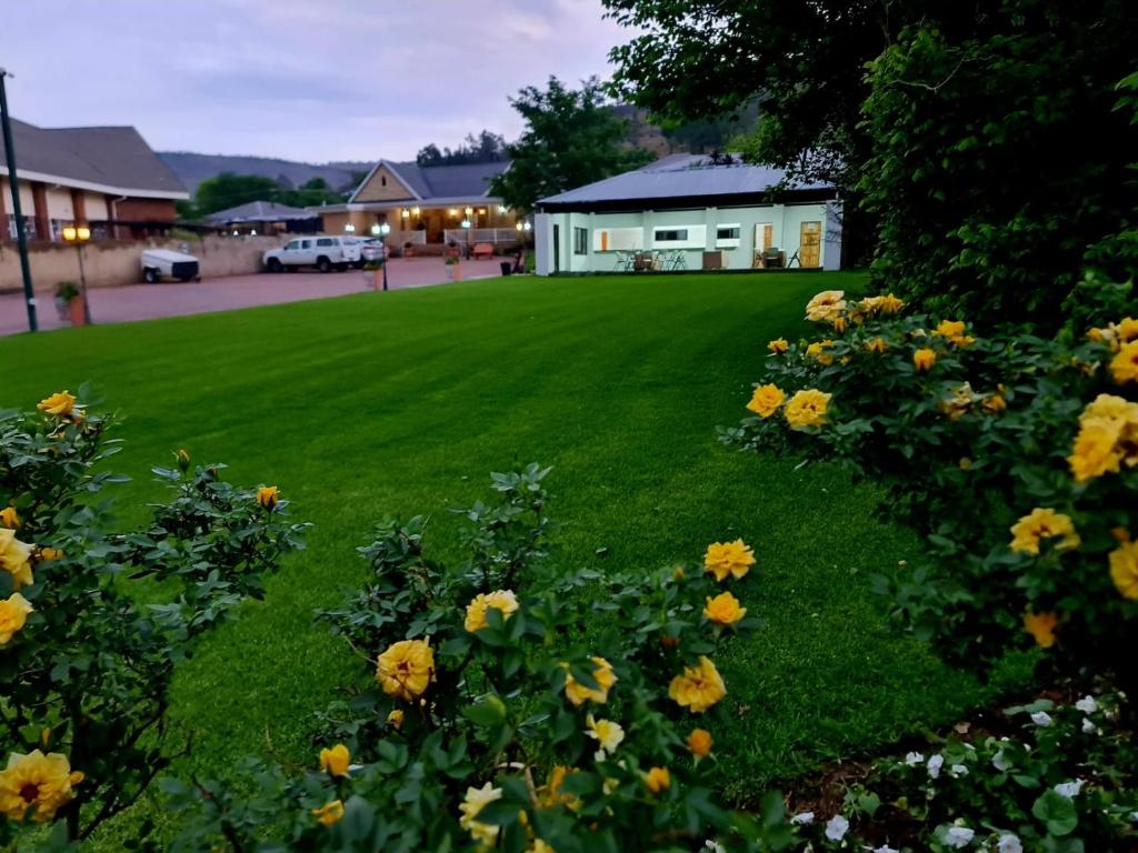 a lawn with yellow flowers in front of a house at Resthaven Guesthouse in Matatiele