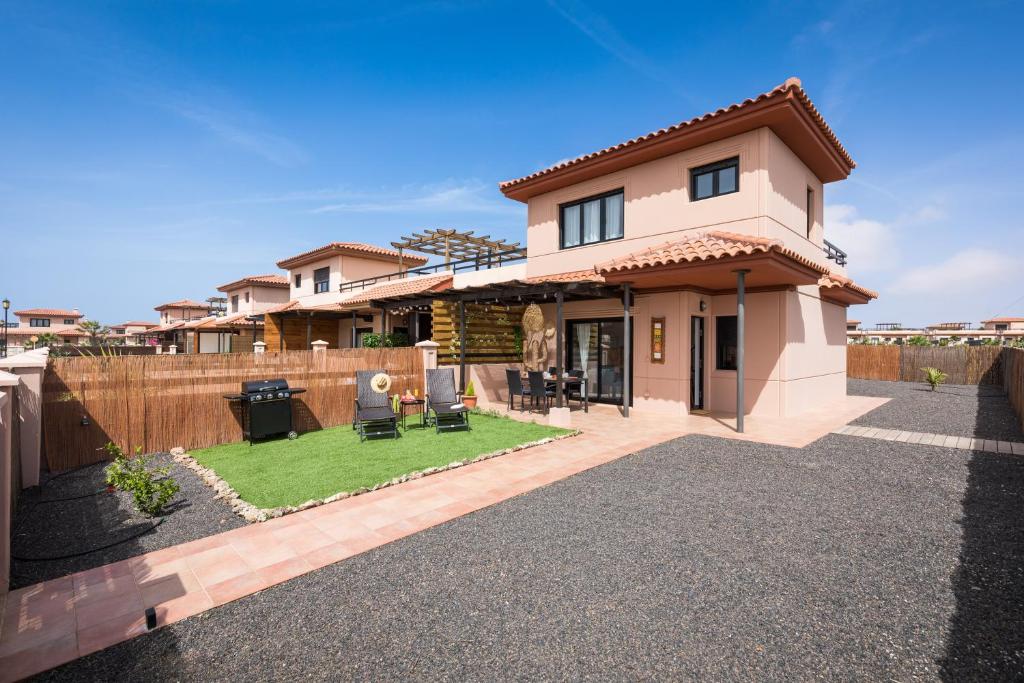 a house with a yard with chairs and a fence at Villa Maha close by the North shore: relax, pool in Lajares