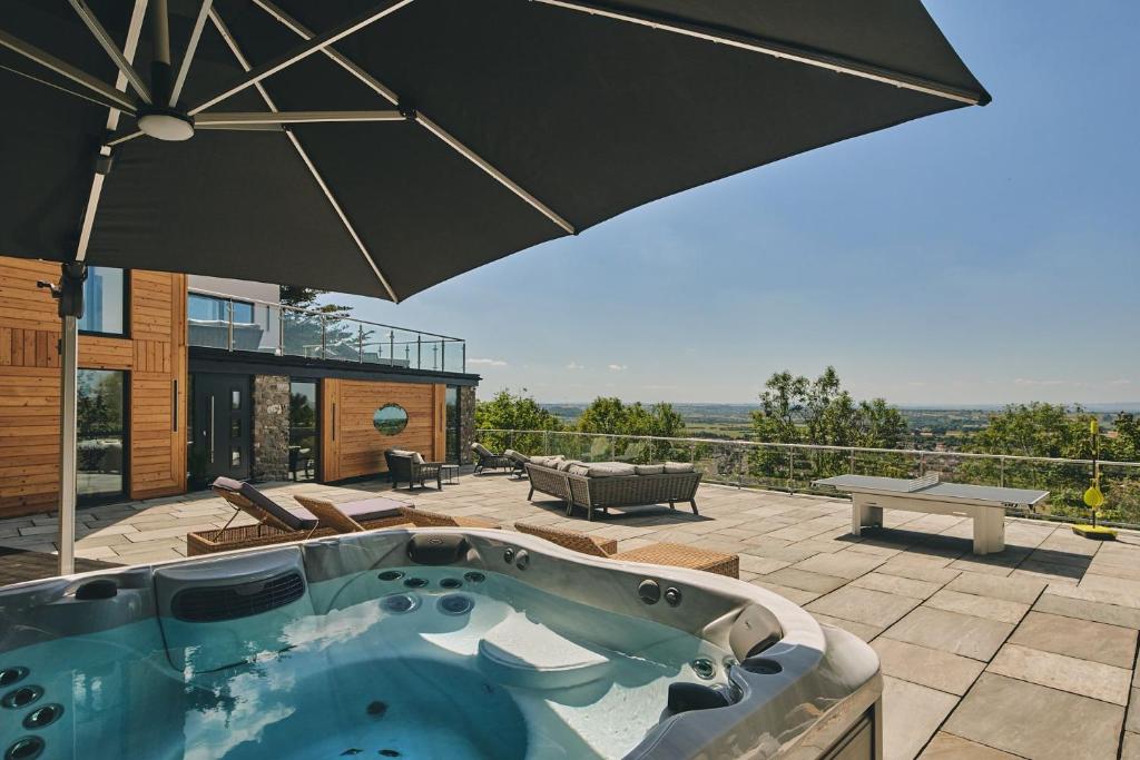a hot tub on a patio with an umbrella at Reservoir View in Cheddar
