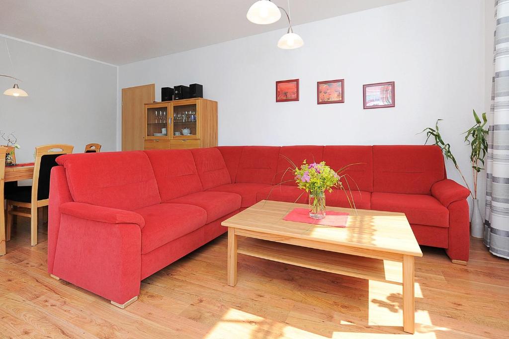 a red couch in a living room with a table at Ferienhaus Möwenweg in Neuharlingersiel
