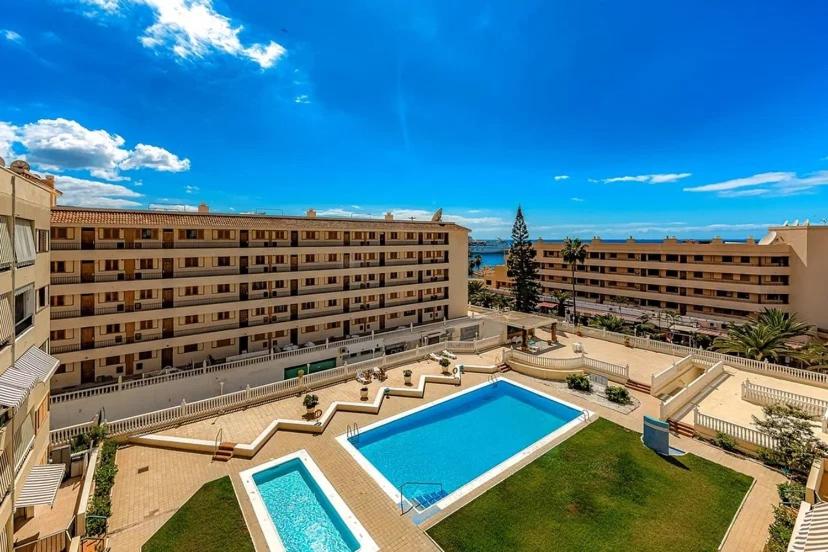 a large building with a swimming pool in a courtyard at Tenerifeopenhome bright penthouse on the beach Los Cristianos in Arona