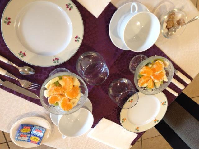 a table topped with plates and bowls of oranges at Chambre d'hôtes Les Nymphéas in Wimereux