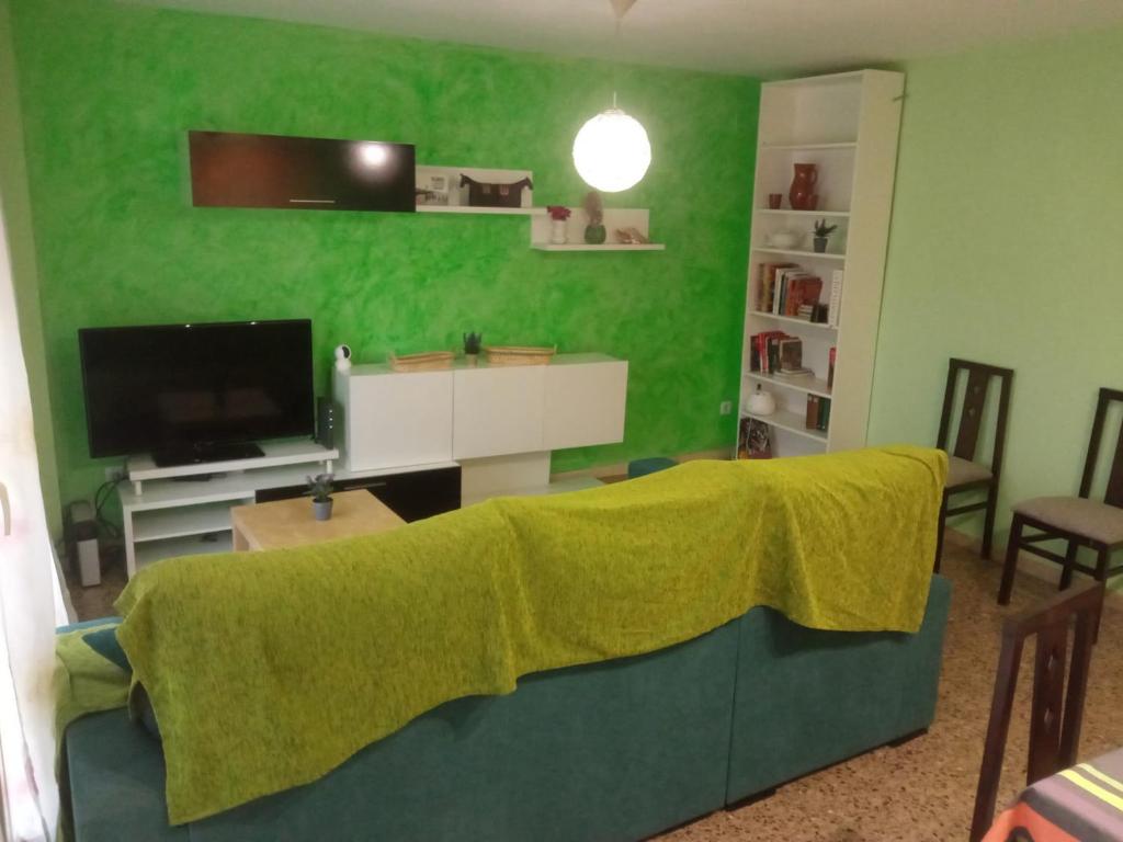 uma sala de estar com um sofá com uma parede verde em Cal Turuta em Vilanova i la Geltrú